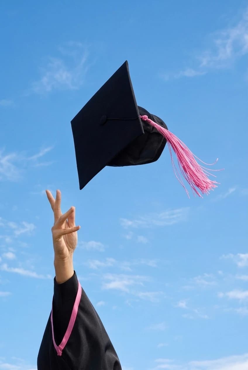 Graduate tossing academic mortarboard cap celebrating degree completion